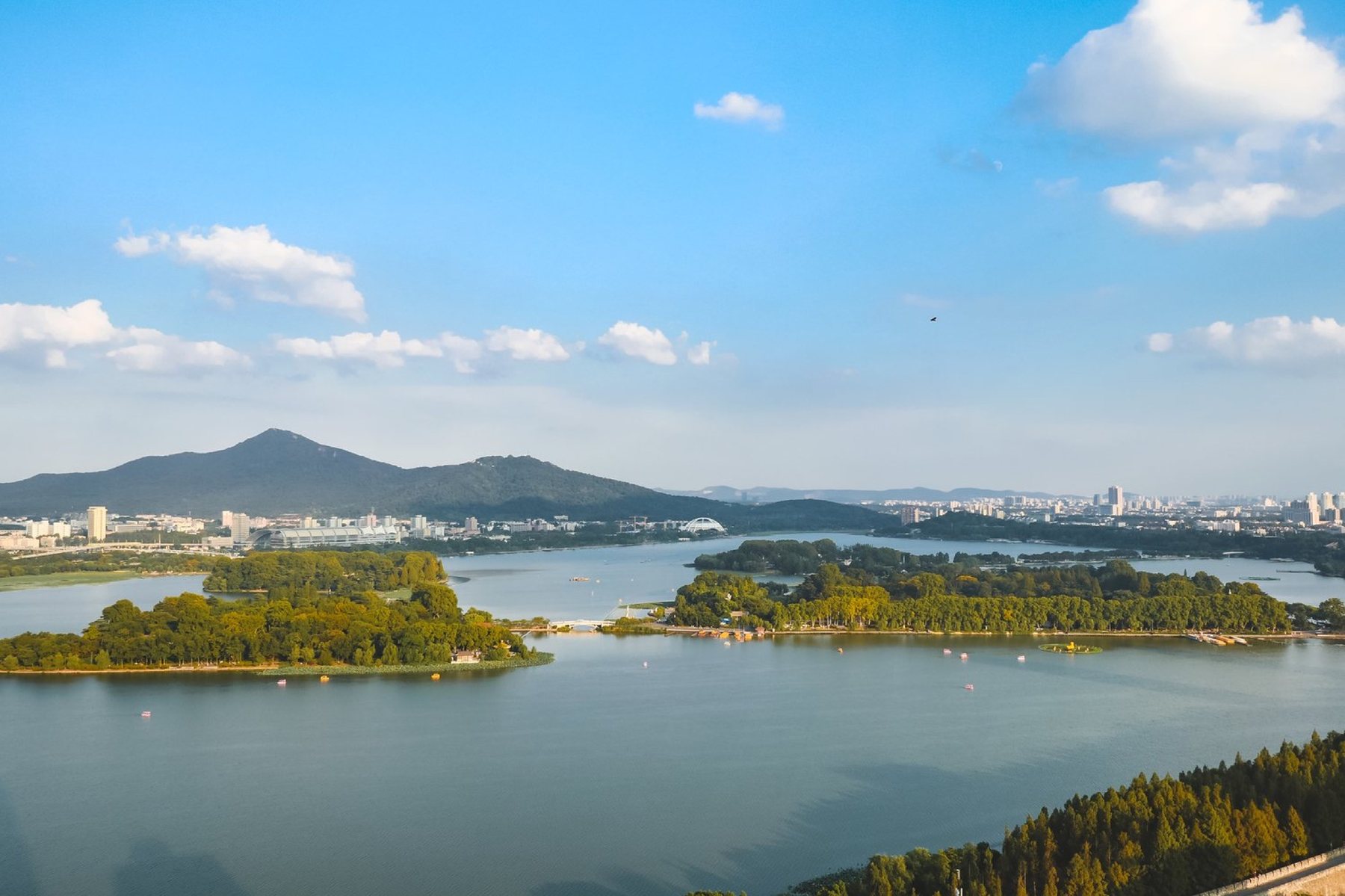 洄游湖景房窗外玄武湖白天景观,画面包含湖面、远山和城市建筑